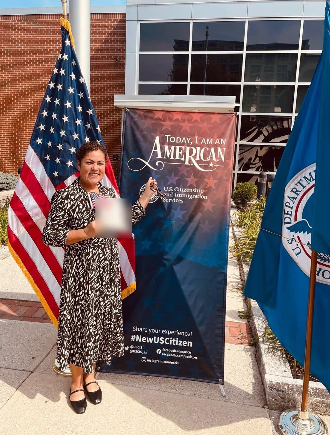 Cliente segurando o certificado de naturalização ao lado da bandeira americana
